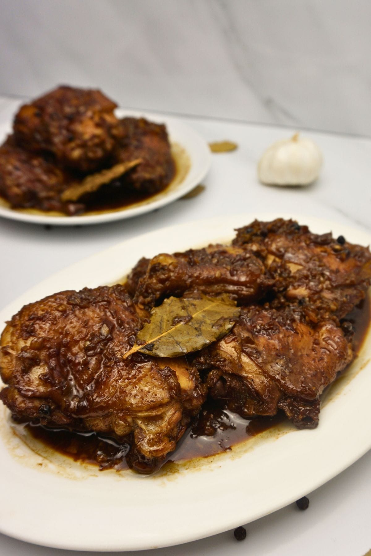 Two plates of chicken on a white marble counter top.