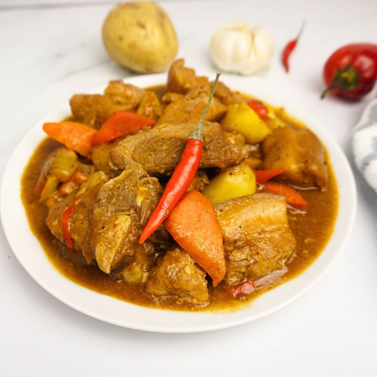 Pork caldereta with red chili on top.