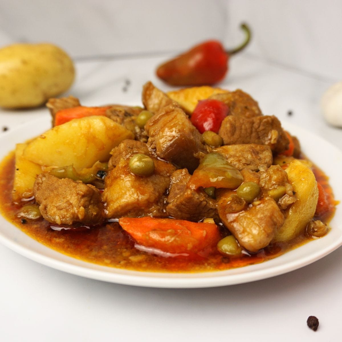 Sliced pork in tomato sauce with carrots, potatoes and bell peppers.