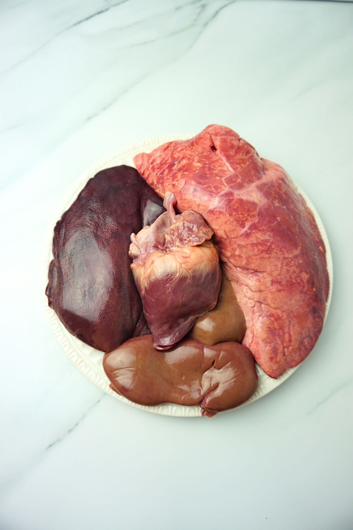 Raw pork lungs, pork kidney, pork liver and pork heart in a plate.