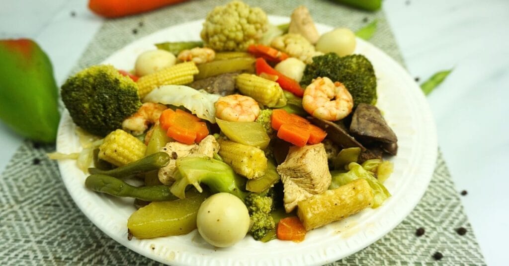 Plate of chopsuey in a table with fresh vegetables.