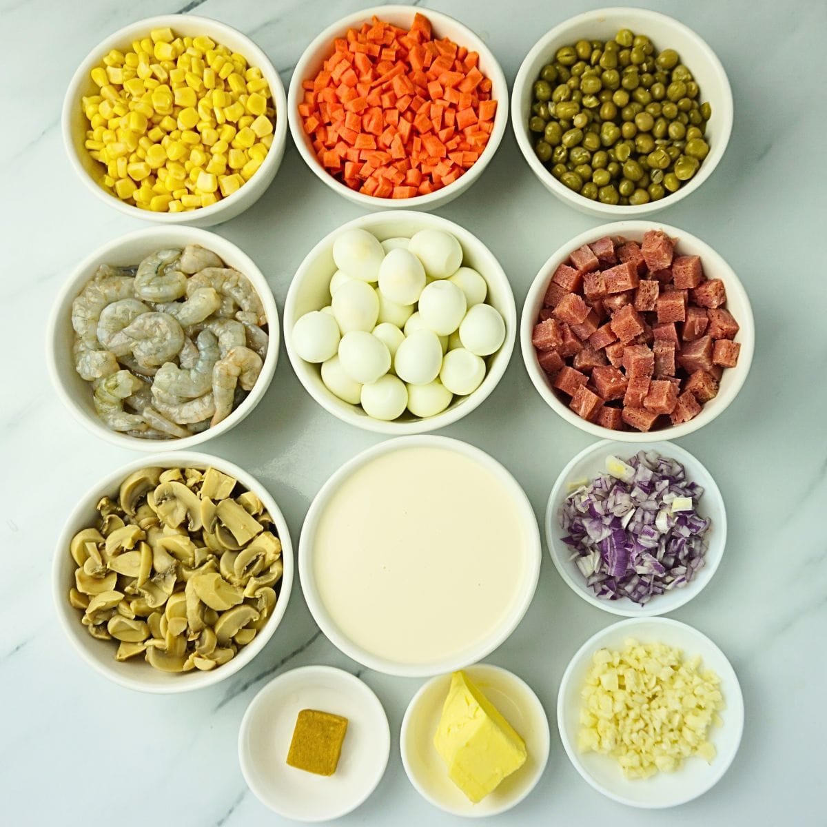 Sipo egg ingredients in bowls. Corn kernels, carrots, green peas, shrimps, quail eggs, ham, mushrooms, all purpose cream, onion, garlic, butter and shrimp cube.