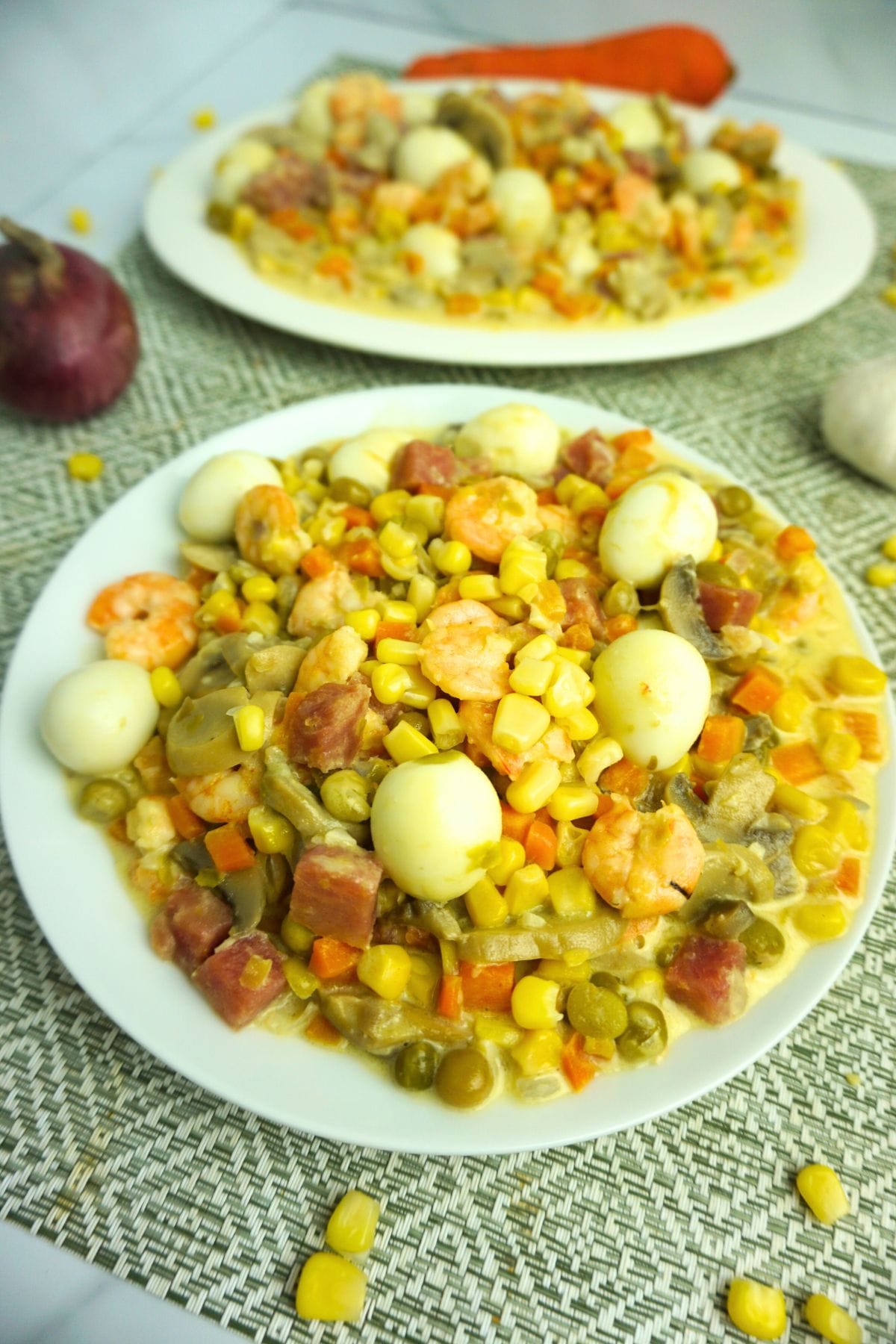Plates of creamy quail eggs. with ham, shrimp, mushrooms, carrots, green peas and corn kernels.