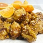 Orange chicken with orange slices on top.