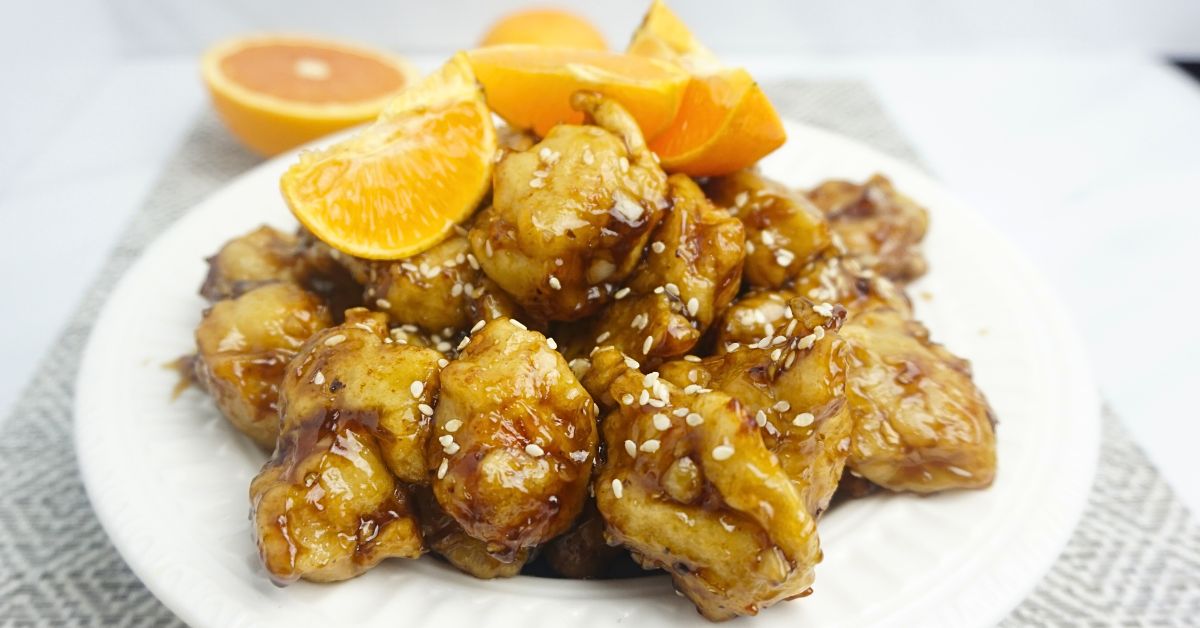 Orange chicken with orange slices on top.