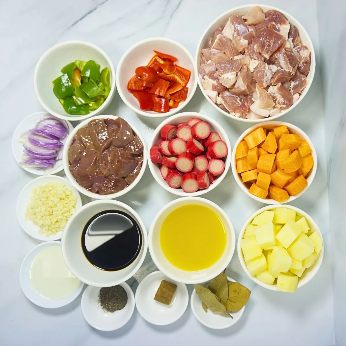 Pork menudo ingredients. Pork shoulder, carrots, potatoes, bell peppers, hotdogs, calamansi juice, soy sauce, bay leaves, pork cube, cooking oil, garlic, onion and pork liver.