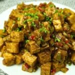 Tofu Sisig in plate garnished chopped green onions.