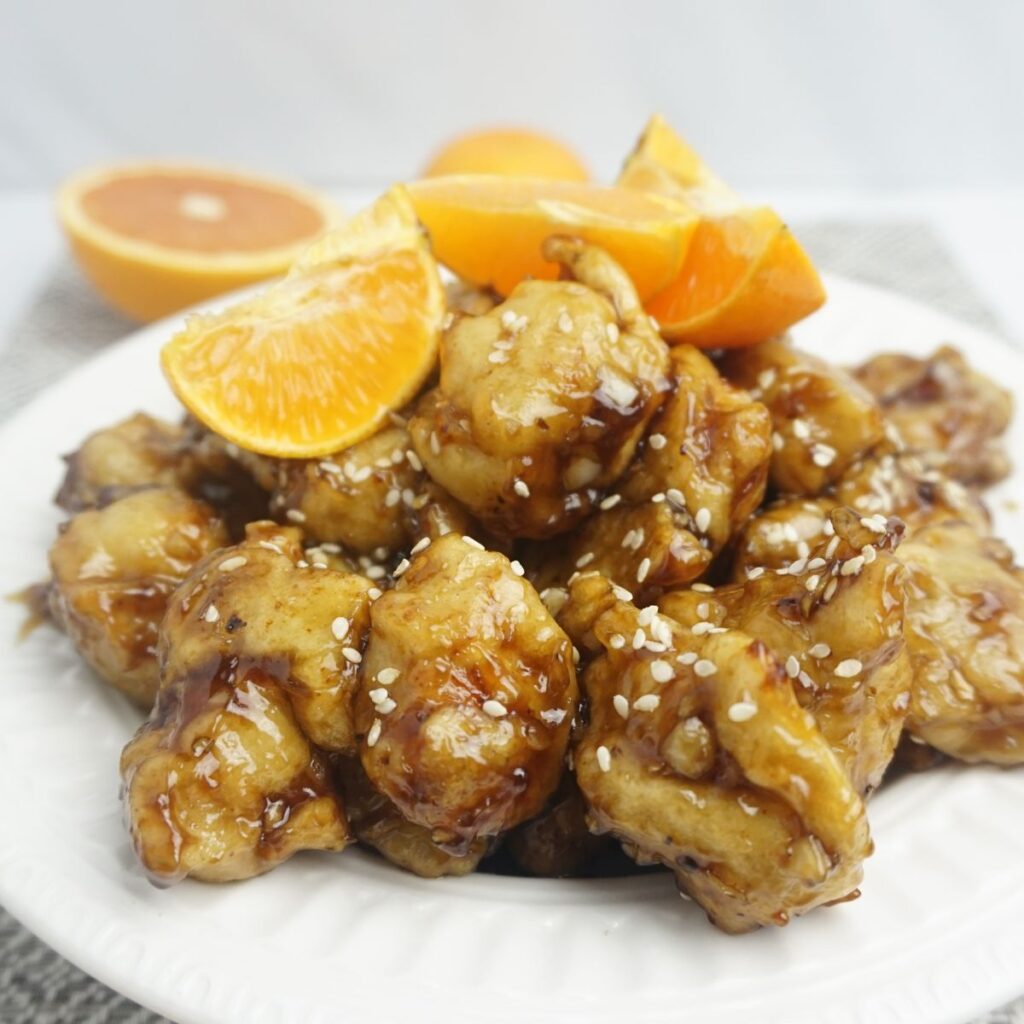 Orange chicken servings in a plate garnished with orange slices.