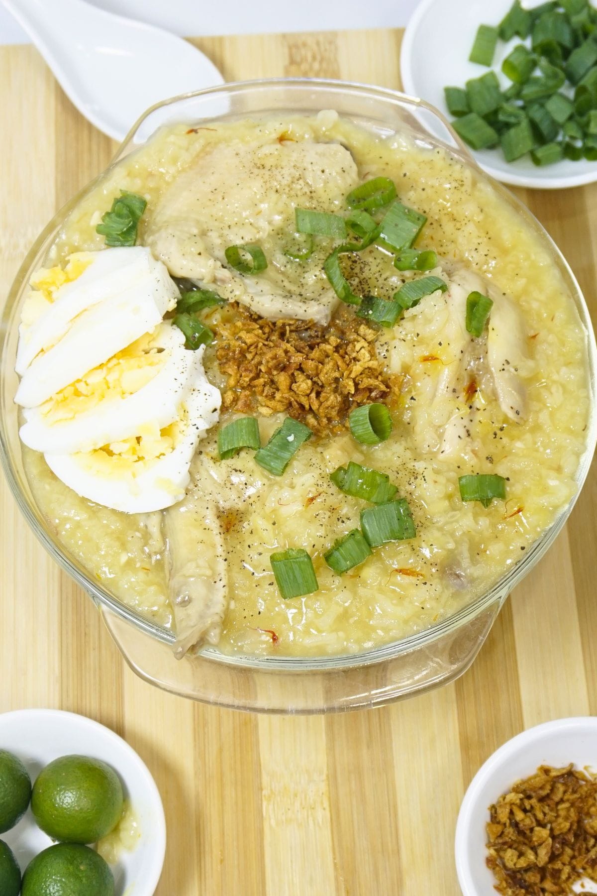 Bowl of arroz caldo with fresh calamansi, green onions and fried garlic.