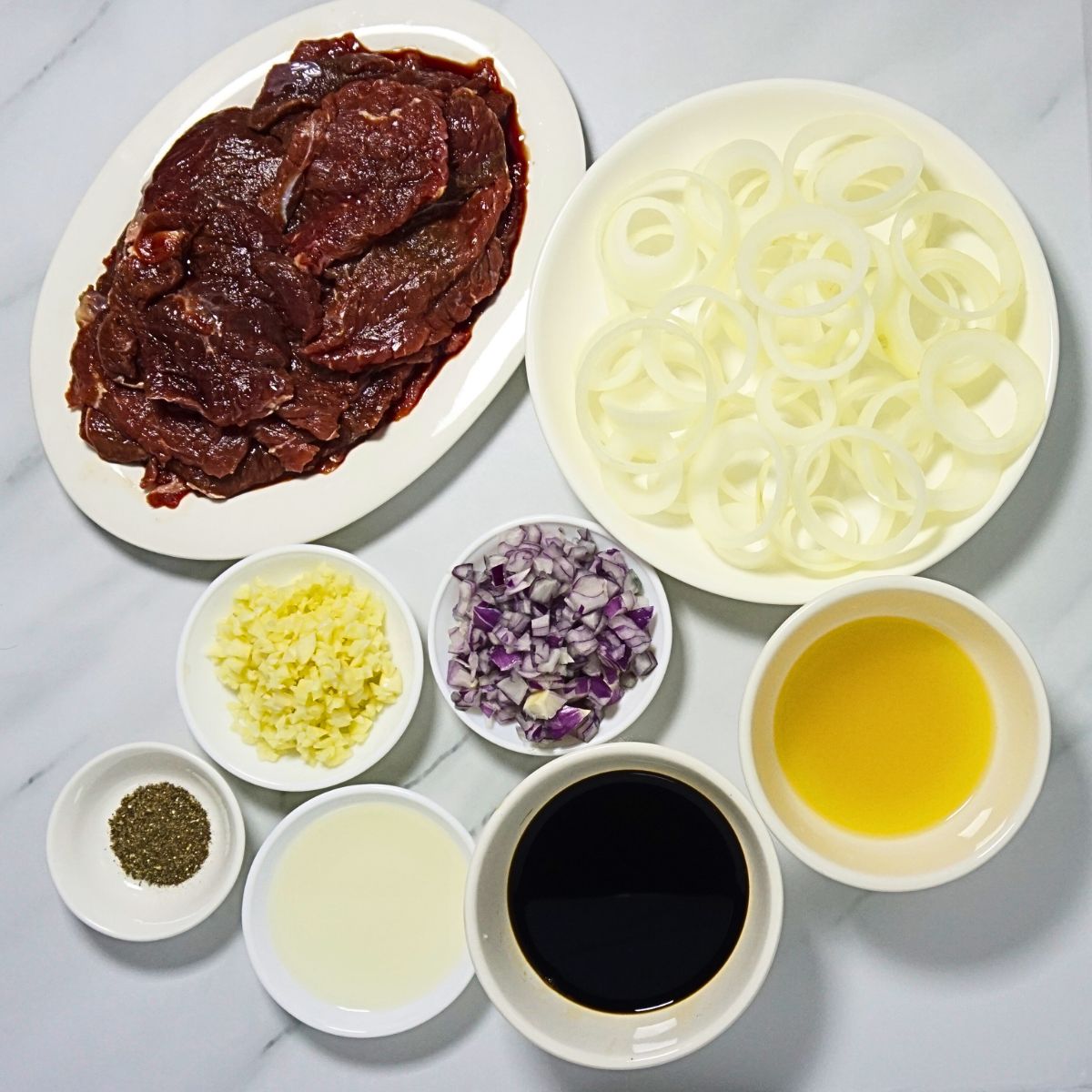 Bistek tagalog ingredients. Beef sirloin, onion rings, garlic, black pepper, cooking oil, soy sauce and calamansi juice.