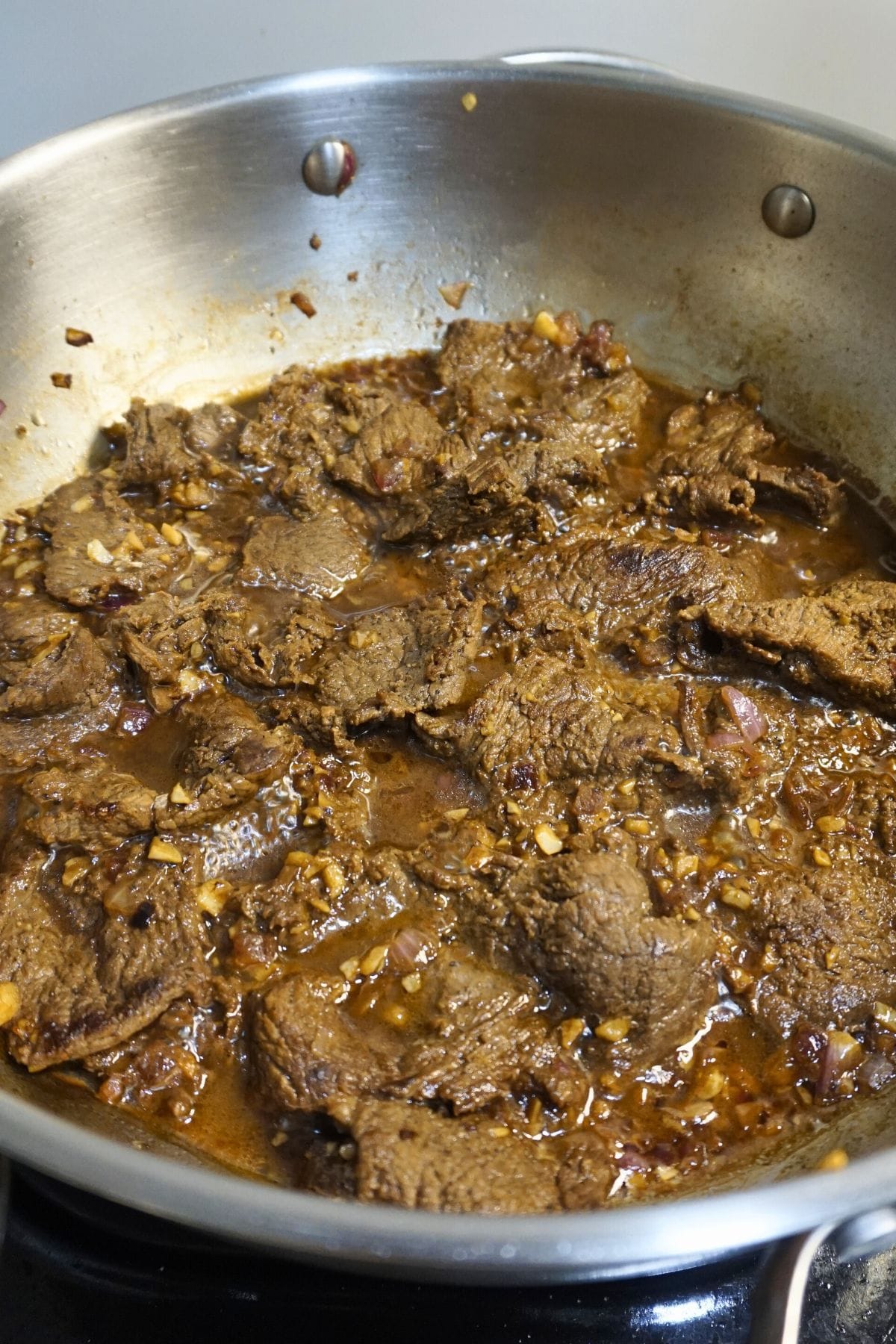 Sauteed beef in soy sauce and calamansi juice in a stainless pan.