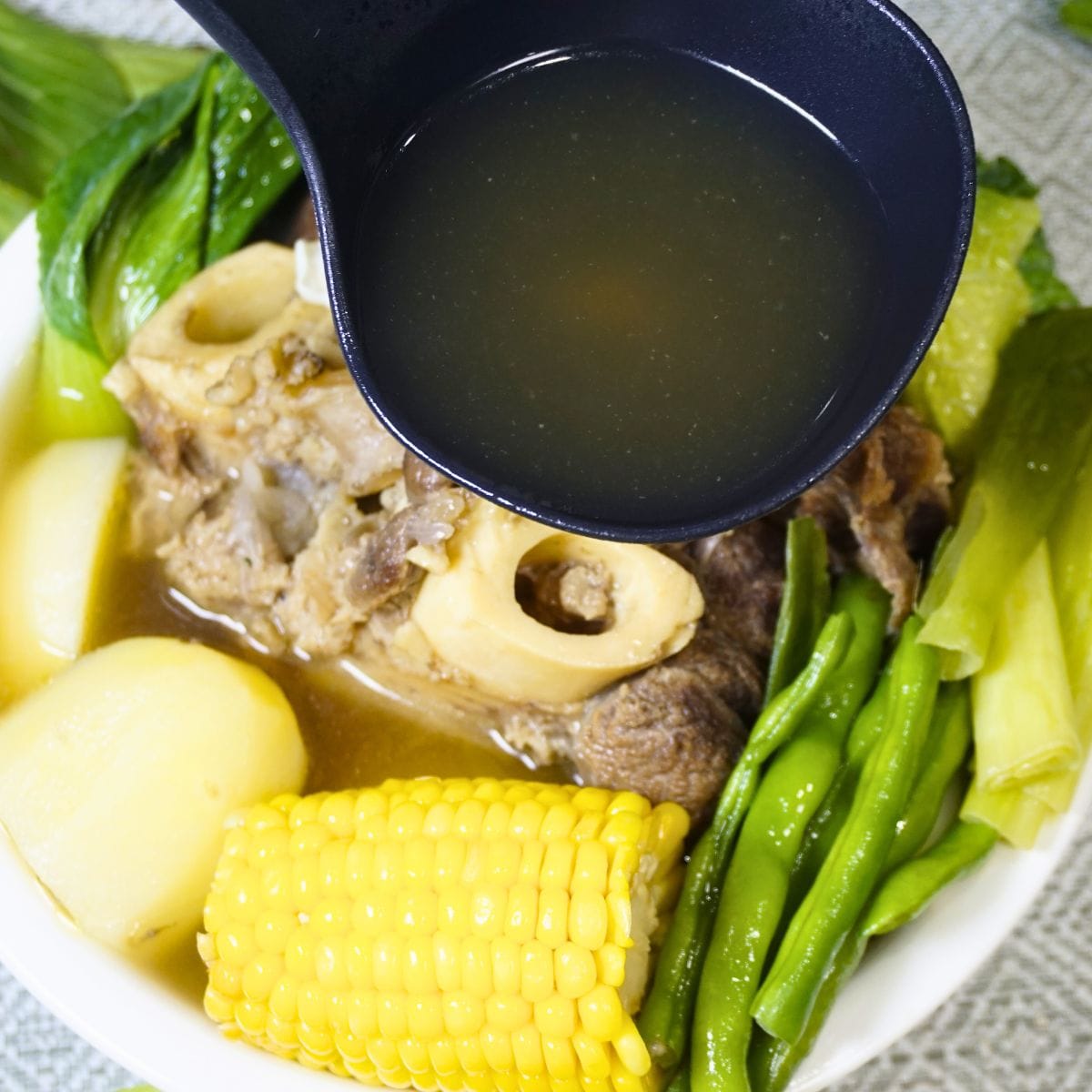 Ladle pouring soup in a bowl of bulalo