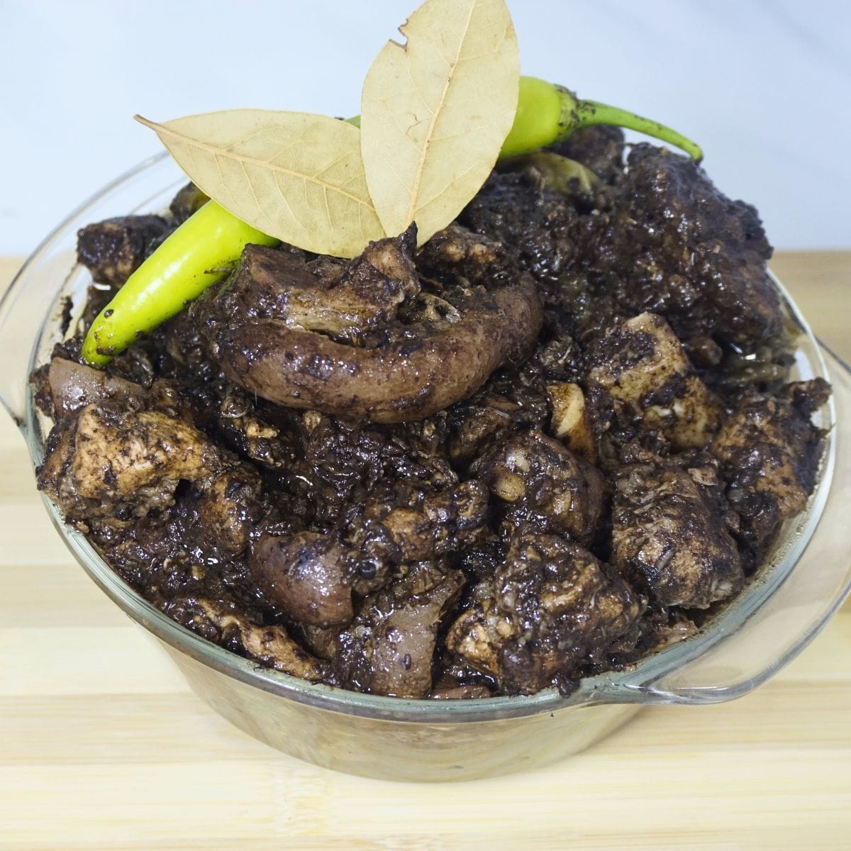 Pork dinuguan garnished with dried bay leaves and fresh green chili.