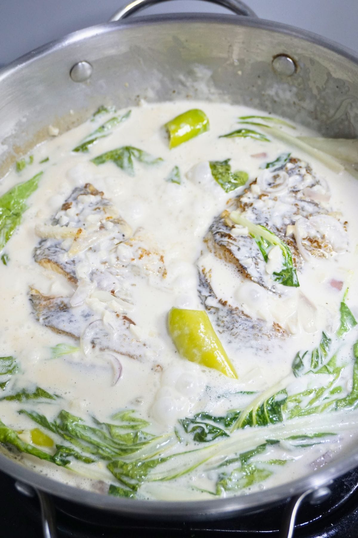Ginataang tilapia in a stainless steel pan.