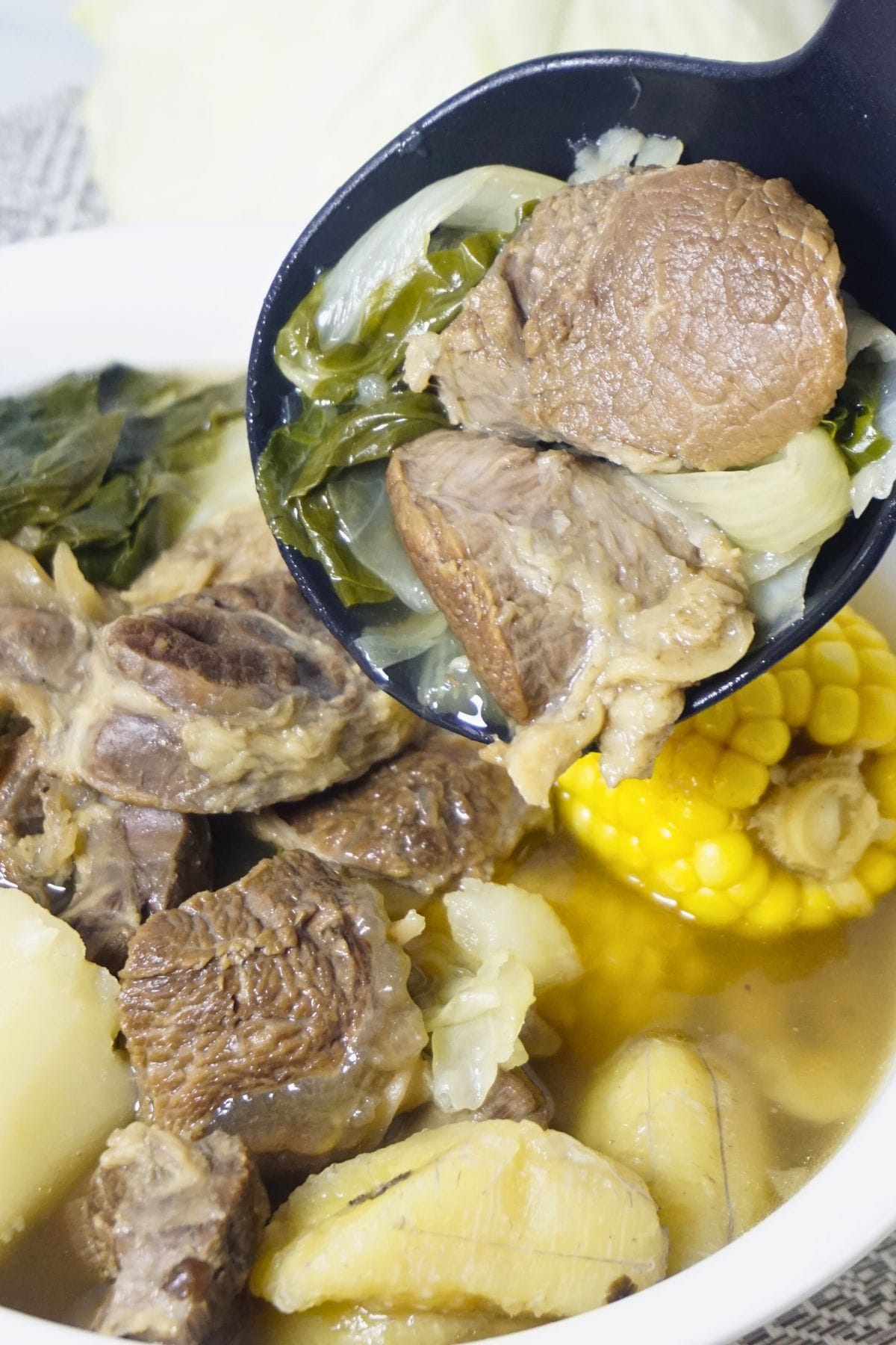 Ladle scooping beef and soup in a bowl of nilagang baka.