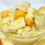 Pininyahang manok in bowl with fresh bell peppers and potatoes in a wooden board.