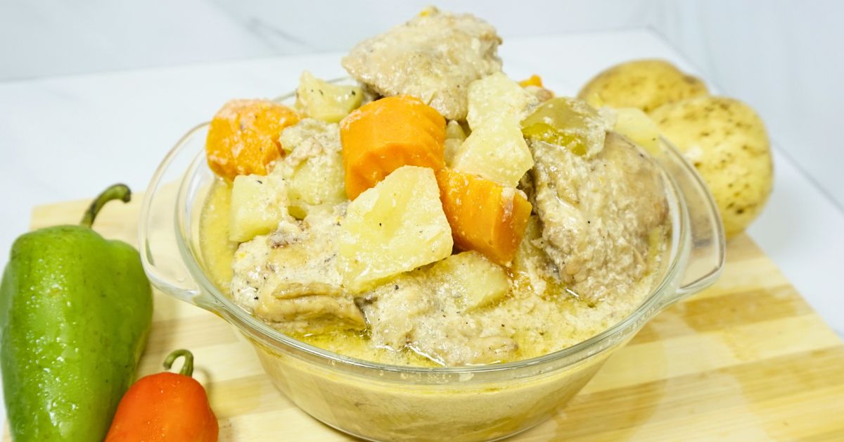 Pininyahang manok in bowl with fresh bell peppers and potatoes in a wooden board.