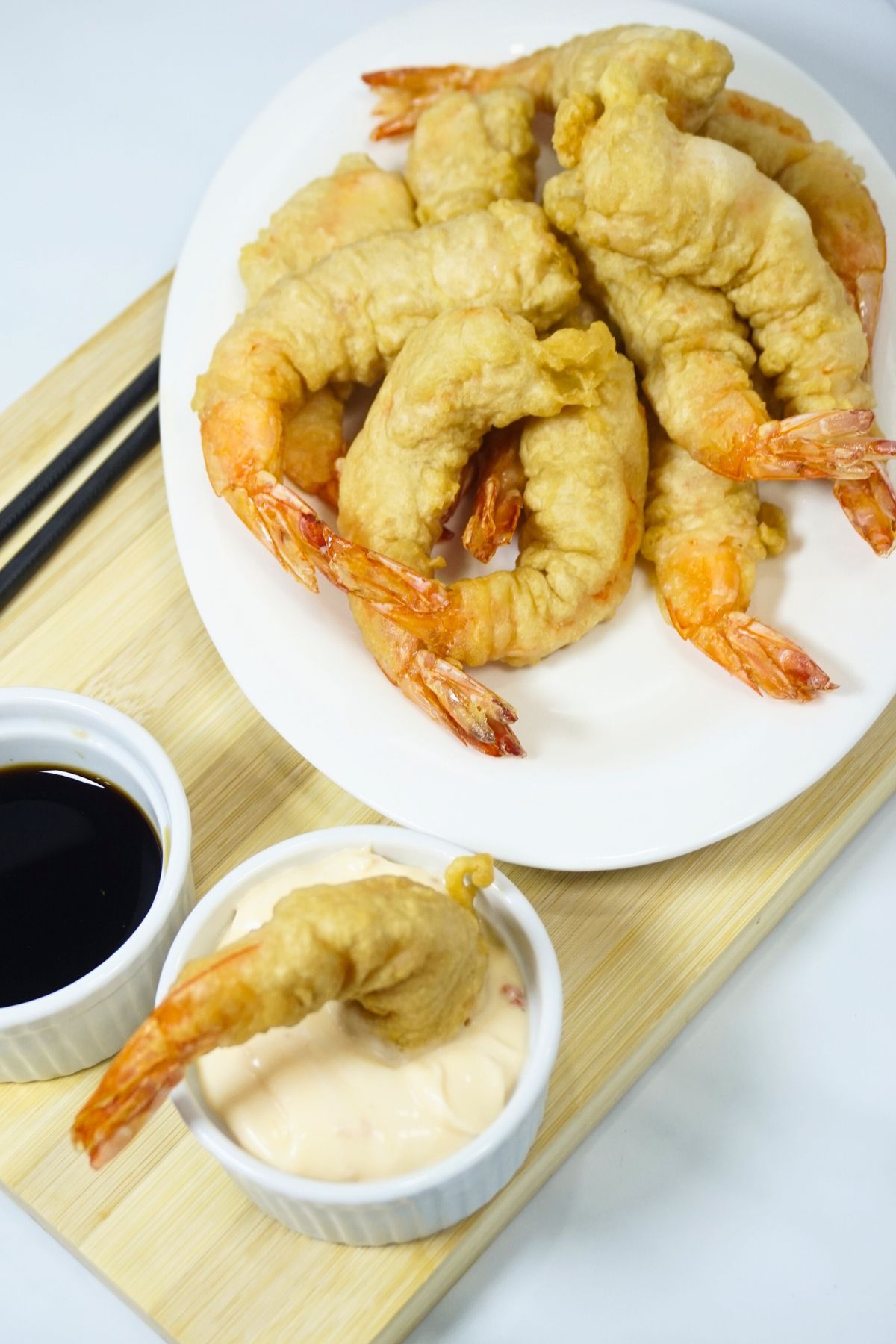 Plate of tempura with one piece dip in mayo-sweet and sour sauce.