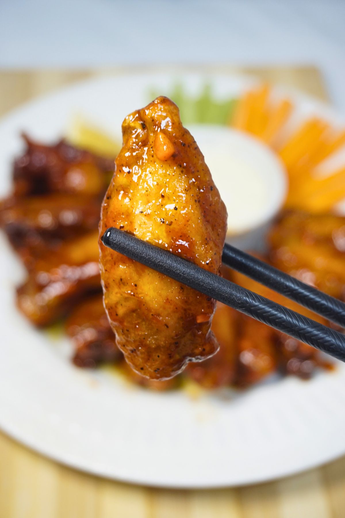 Chopsticks holding crispy and spicy buffalo wings.