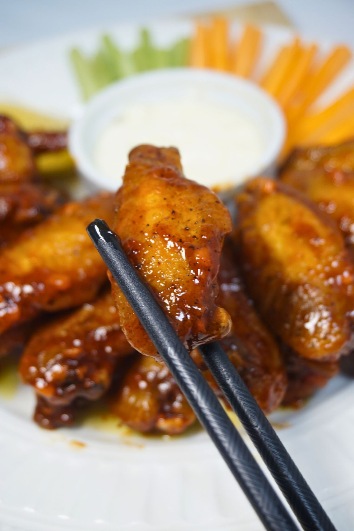 Buffalo wings on a pair of chopsticks.