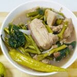 Bowl of pork bulanglang with fresh guavas and green chili in a wooden cutting board.