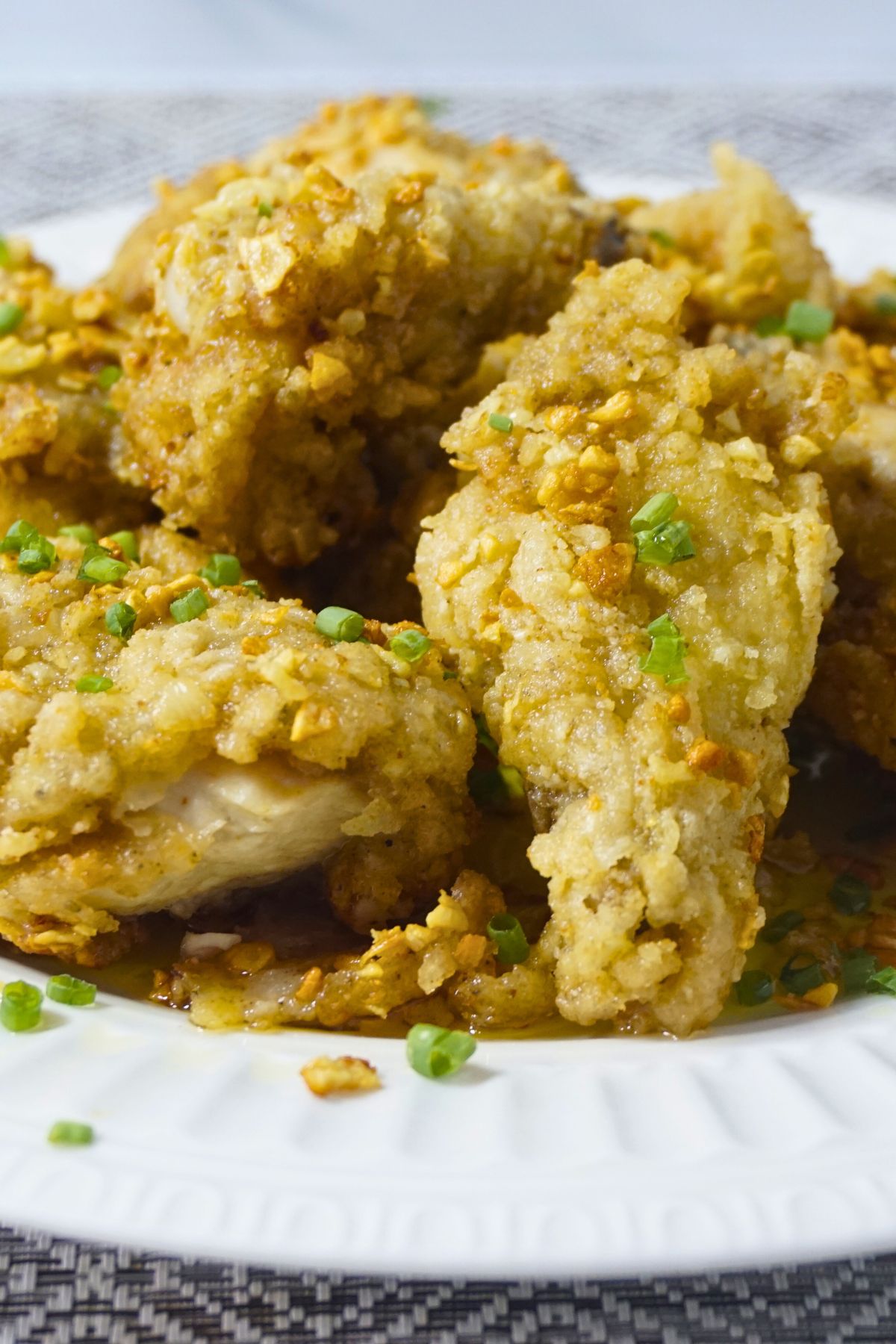 Coated fried chicken slices with butter and garlic, garnished with spring onions.