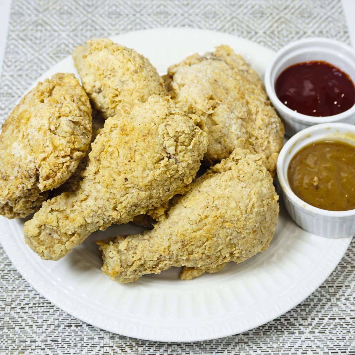 Plate of deep fried chicken with gravy and ketchup dipping sauce.