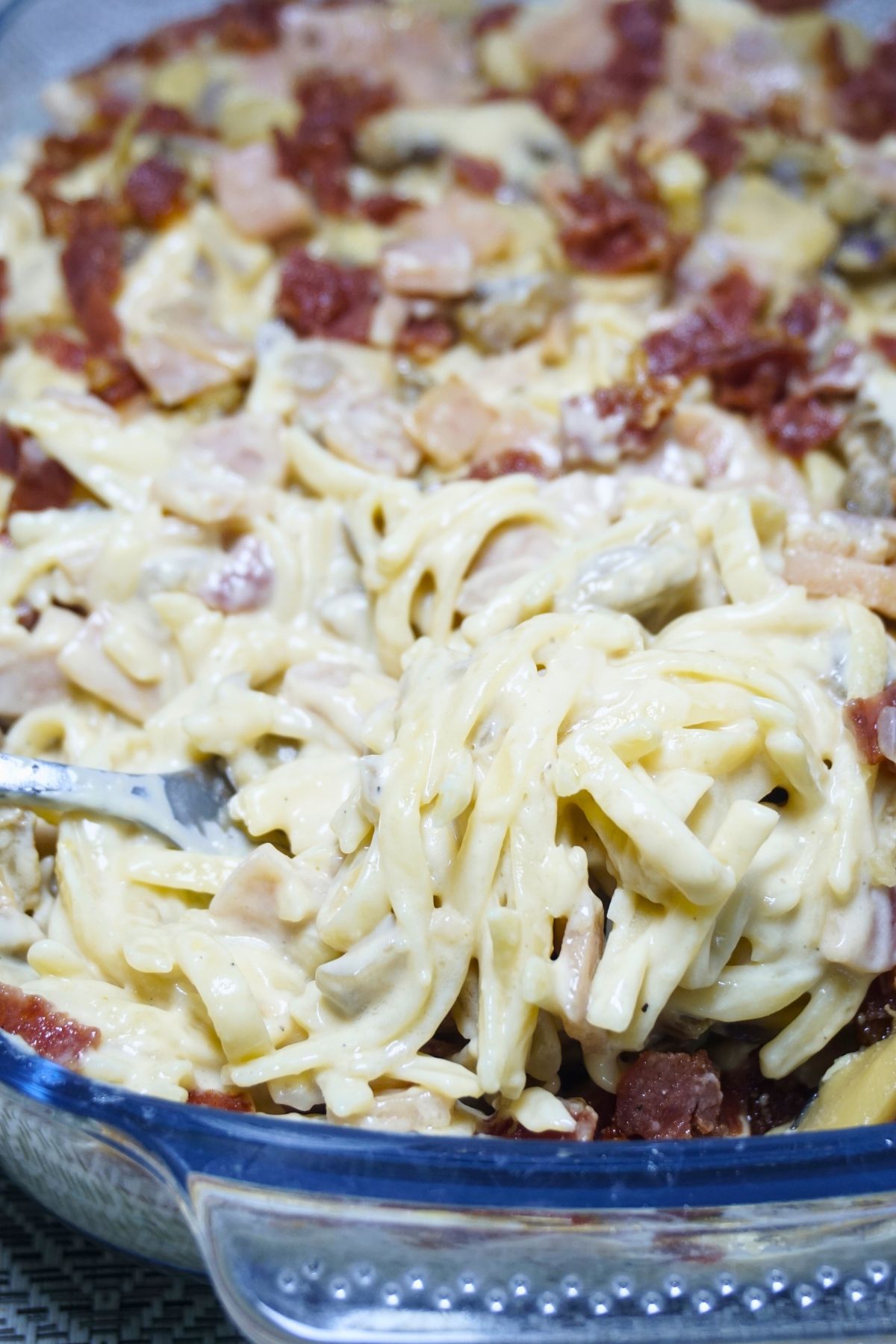 Fork scooping a portion of Filipino style carbonara.