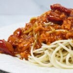 Plate of spaghetti with grated cheese on the side.