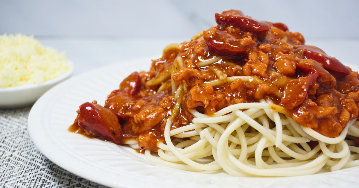 Plate of spaghetti with grated cheese on the side.