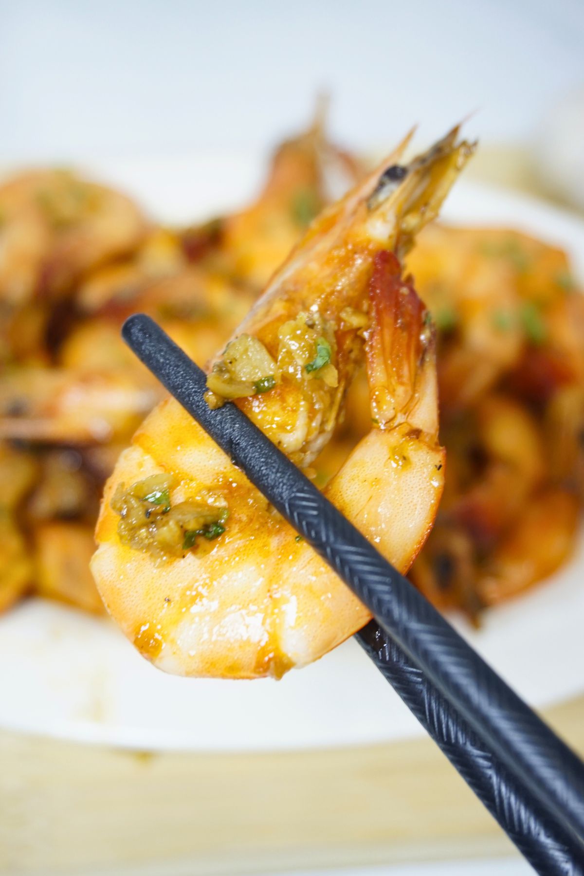 Chopsticks holding a piece of sauteed shrimp.