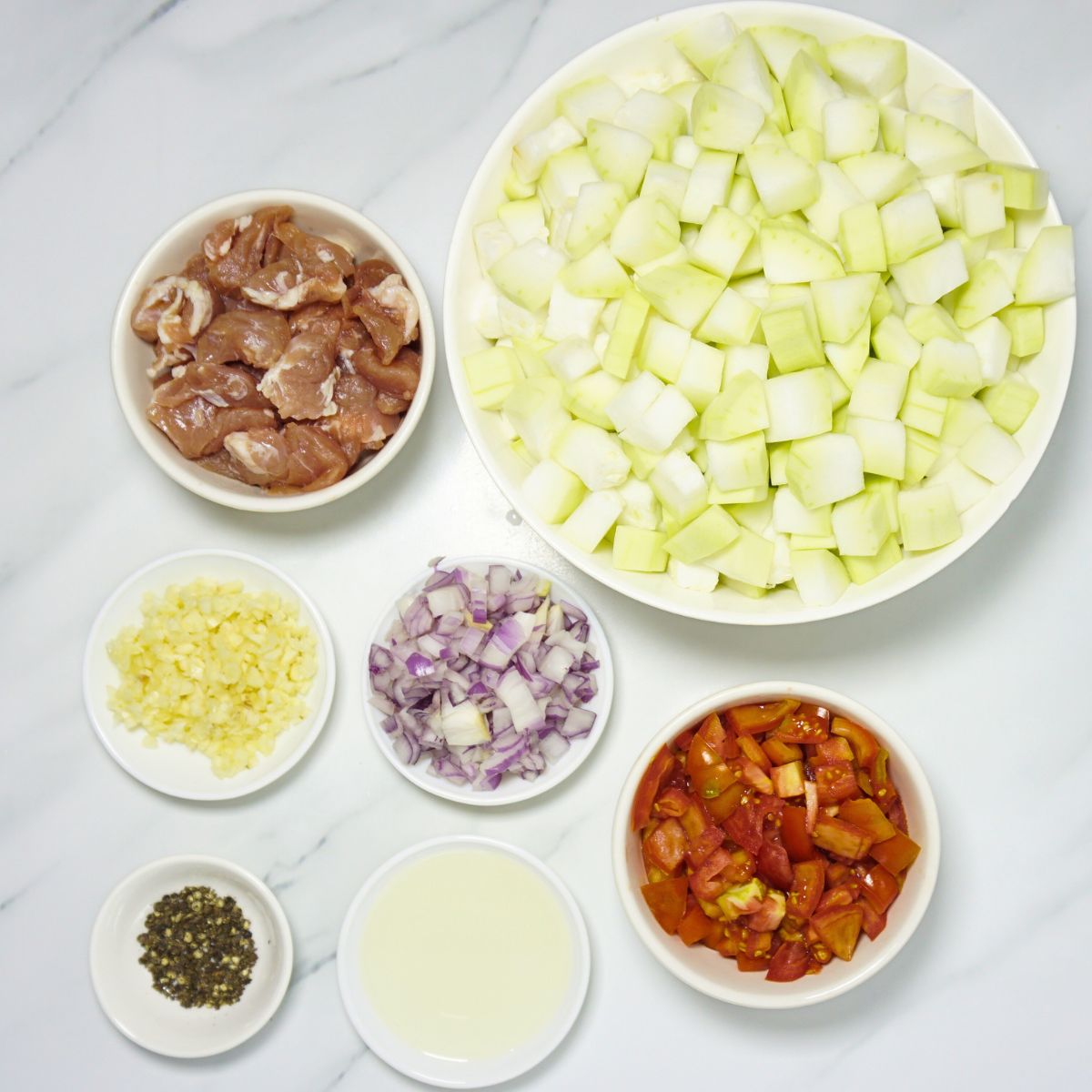 Ginisang upo ingredients. Sliced pork belly, cubed bottle gourd, cooking oil, garlic, onion, tomatoes and black pepper.