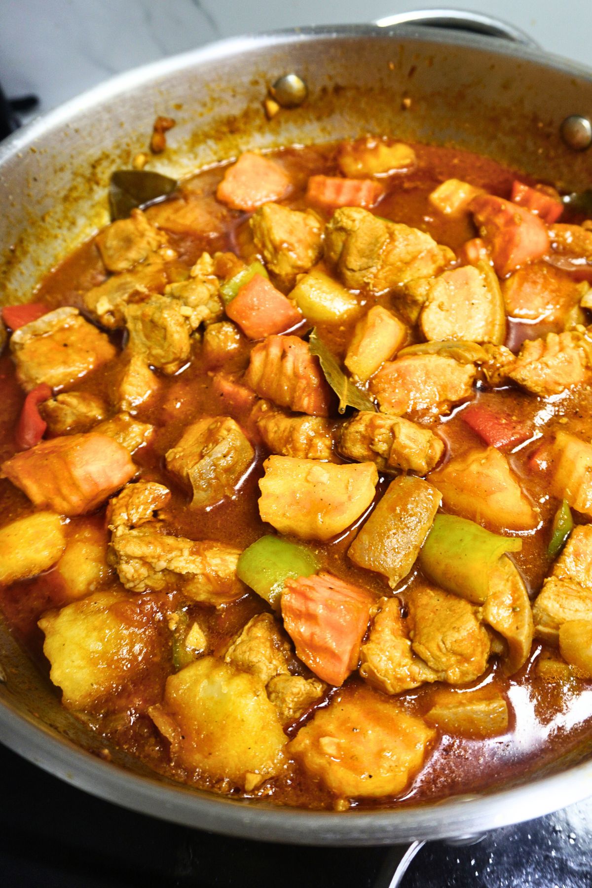Pork afritada cooked in a stainless steel pan.