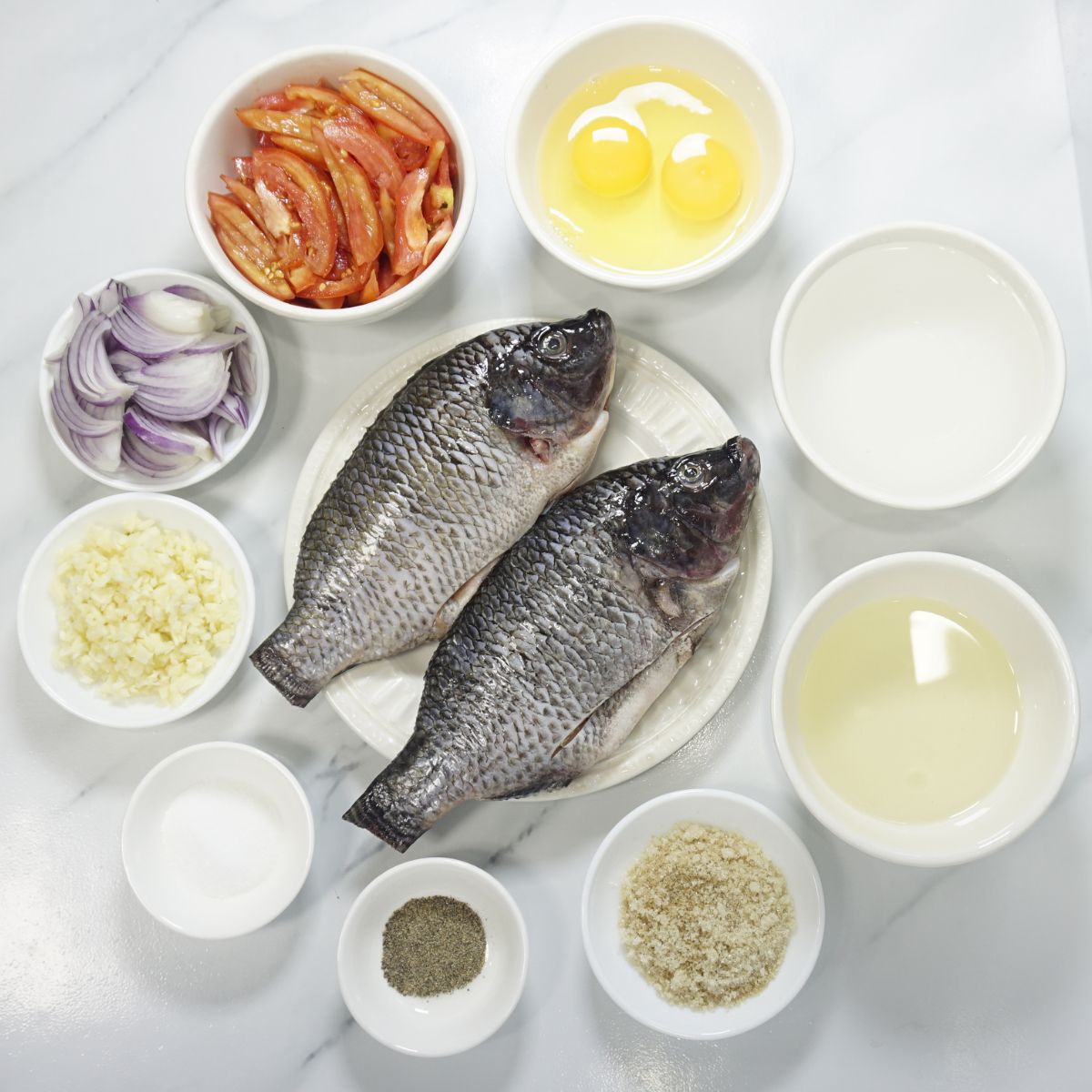 Sarciadong tilapia ingredients. Tilapia, cooking oil, garlic, onion, tomatoes, water, sugar, salt and pepper.