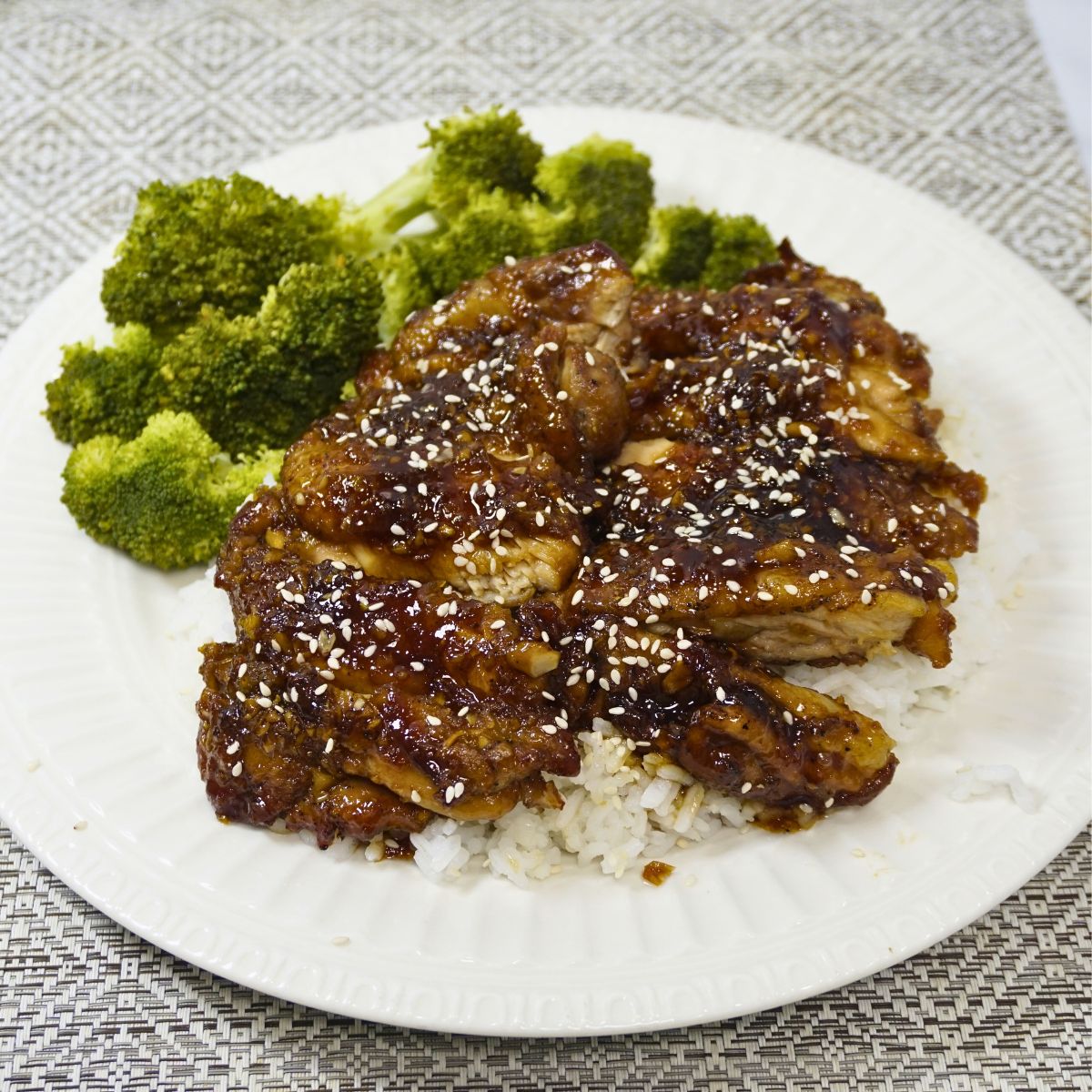Chicken thigh covered in teriyaki sauce with sesame seeds on top.