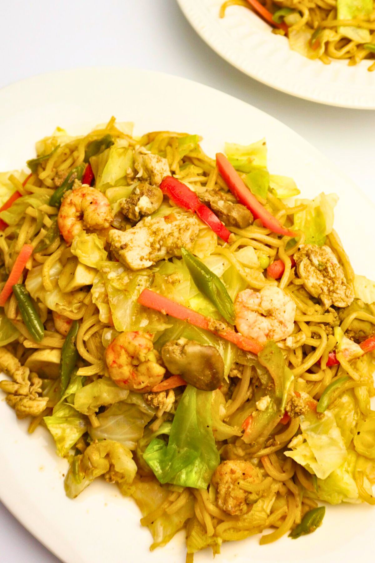 Servings of pancit canton with vegetables in plate.