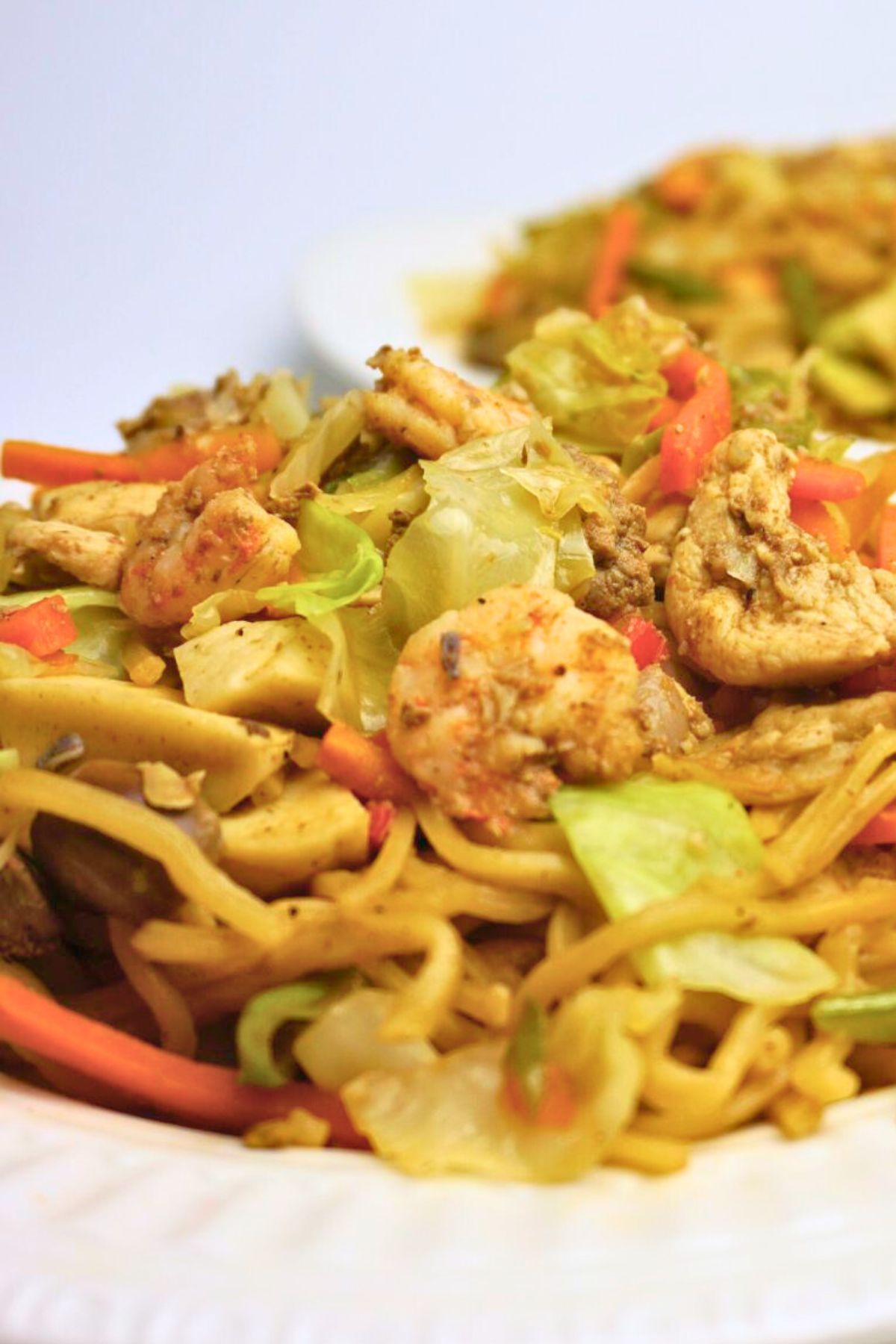 Pancit canton with lots of vegetable served in a white plate.