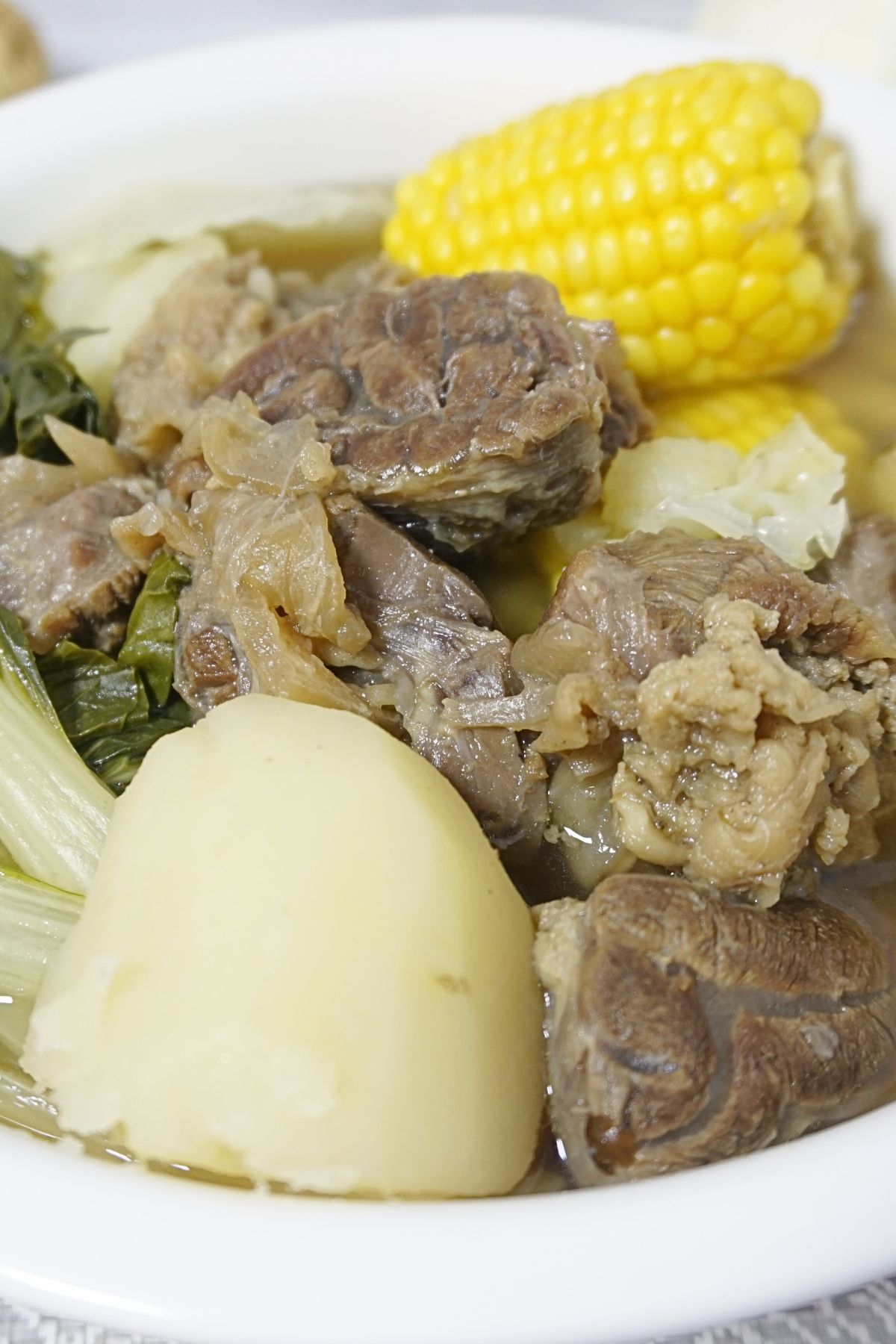 Beef nilaga serving with vegetables in a white bowl.