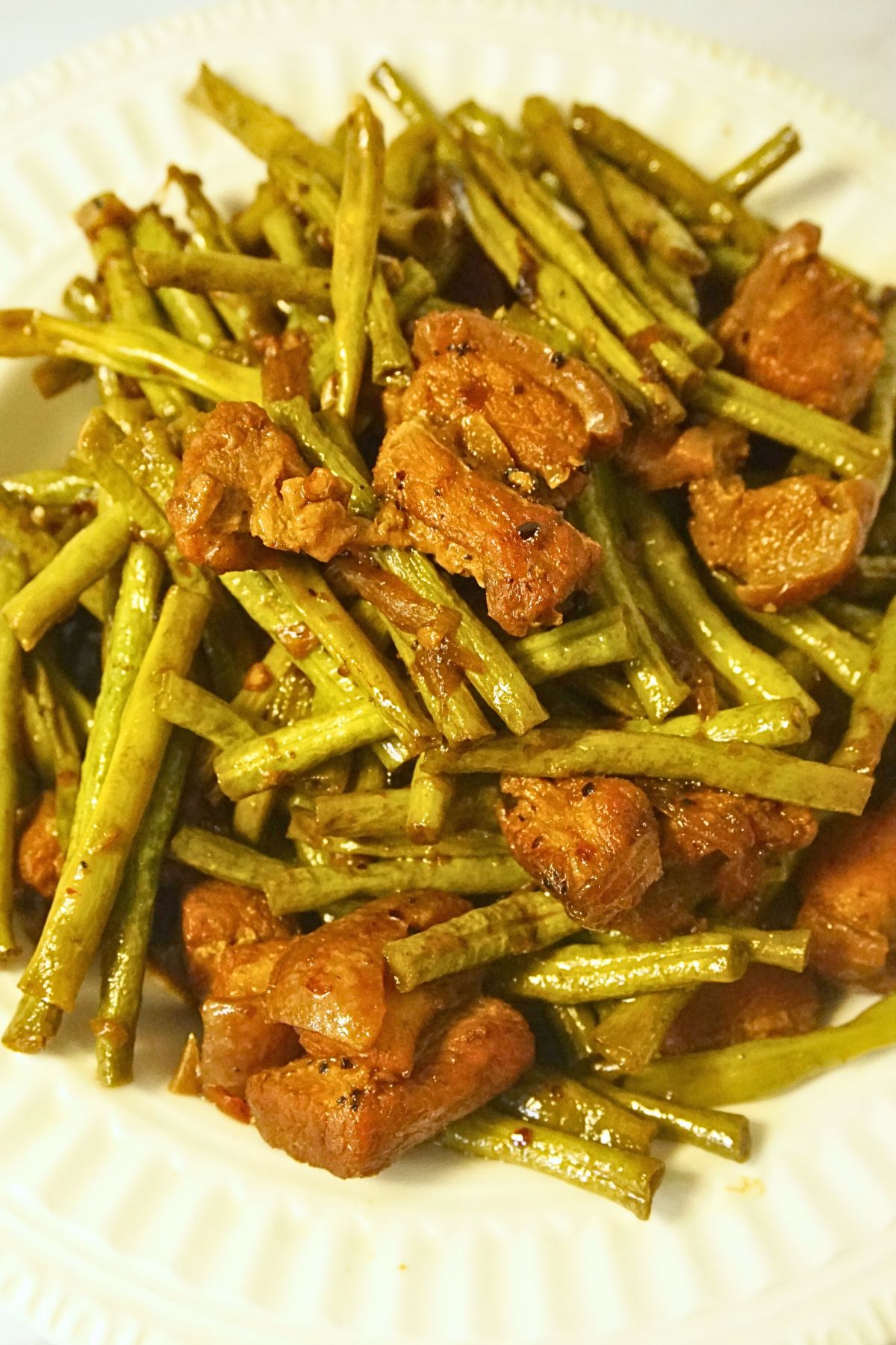 Close-up of Adobong Sitaw featuring pork belly and string beans on a clean white plate