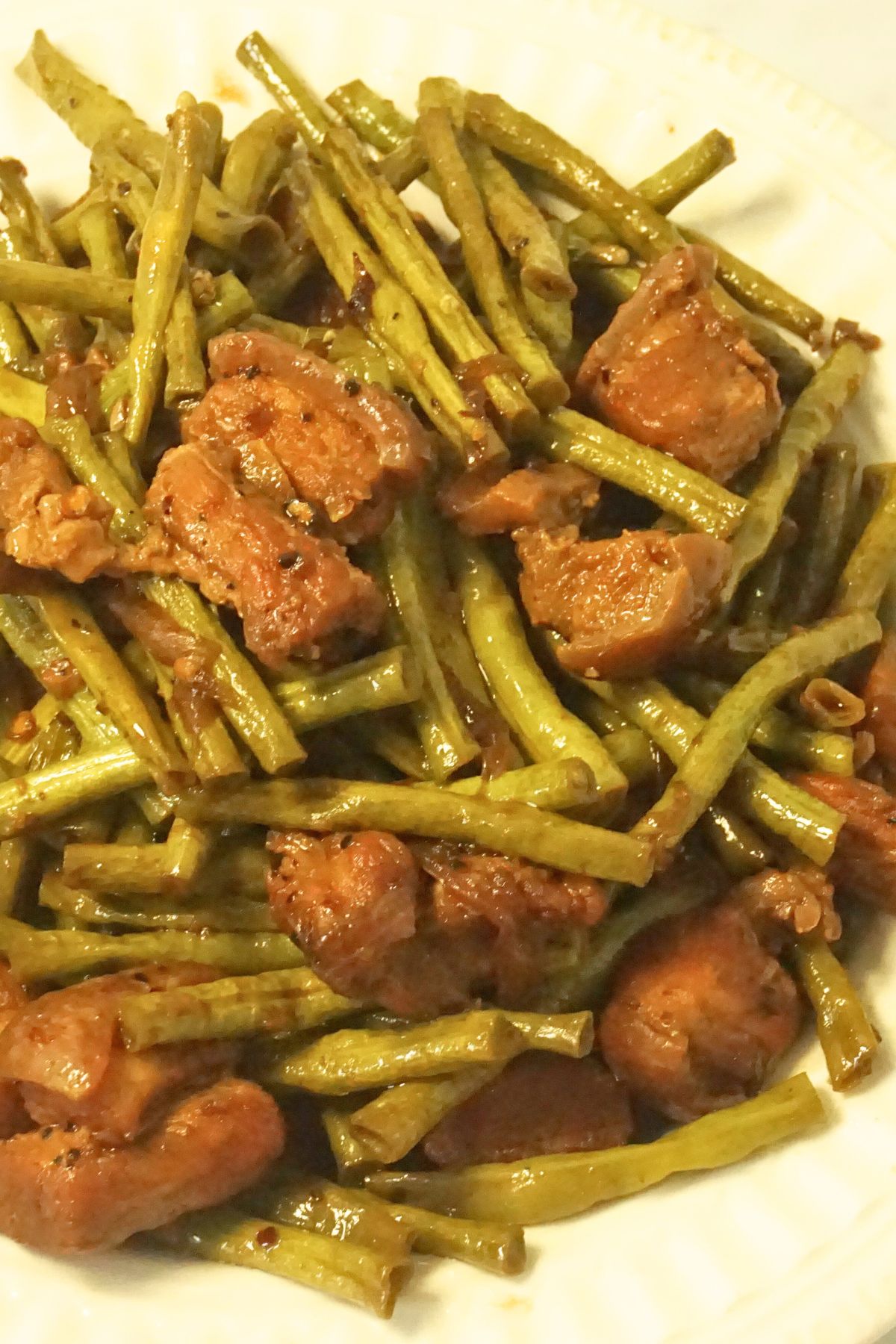 Adobong sitaw with tender pork belly slices served on a white plate,