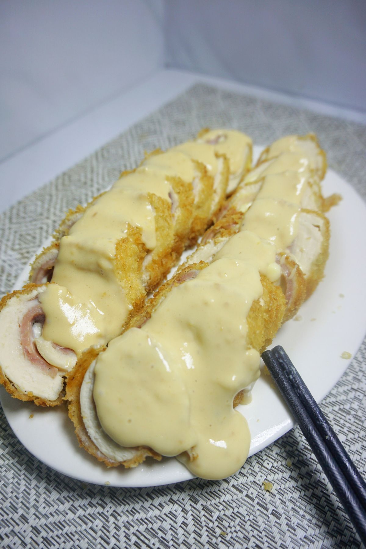 Sliced chicken cordon bleu topped with white sauce