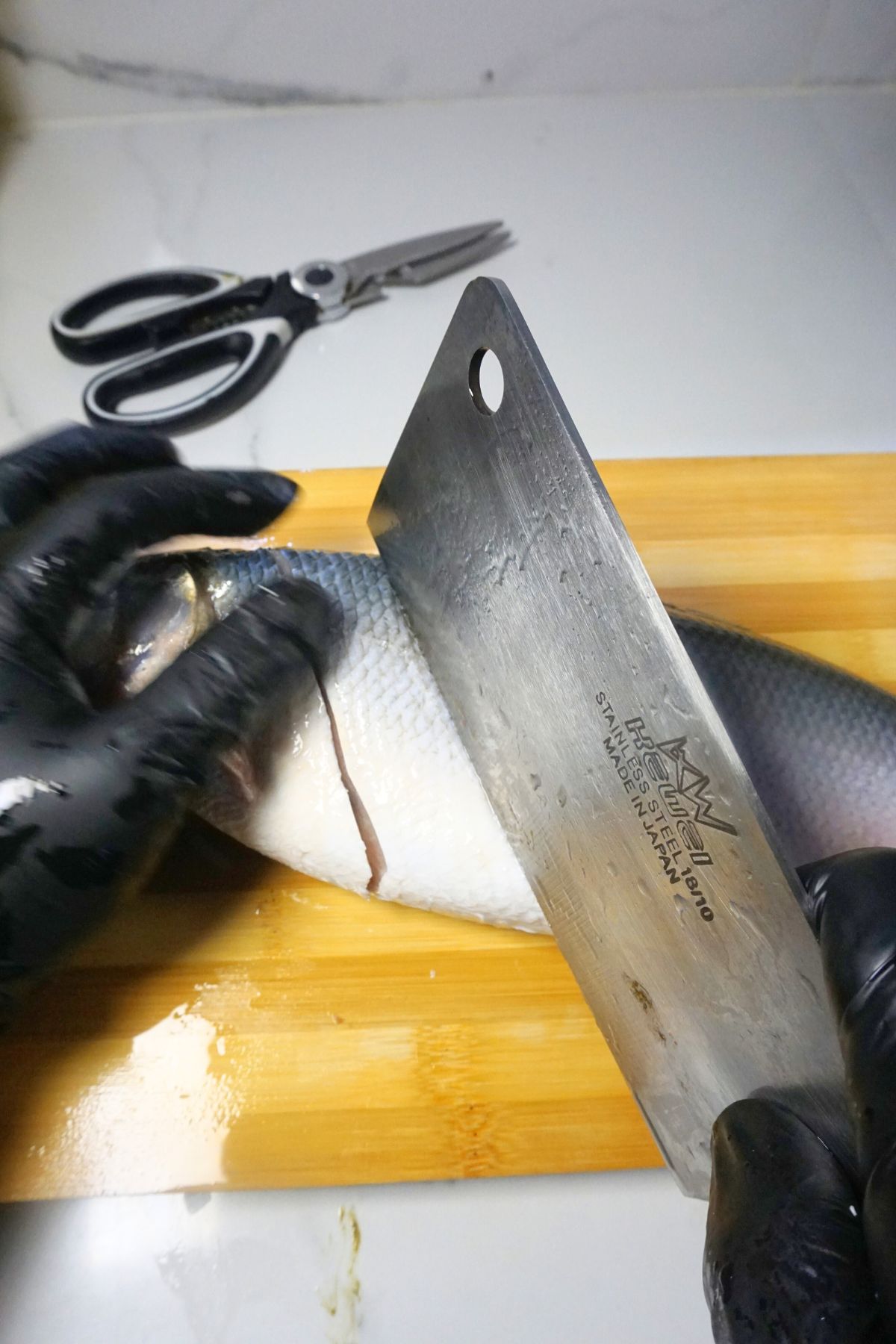 Cutting cleaned bangus into equal serving portions on a cutting board