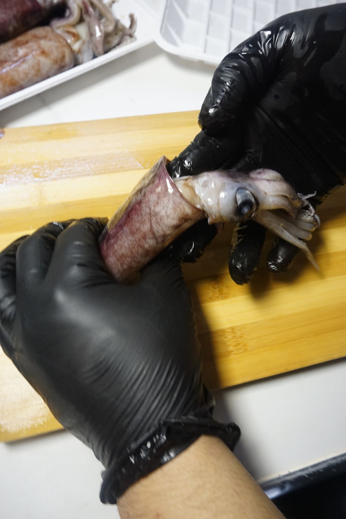 Pulling the squid’s head and tentacles away from the body to remove most of the innards.