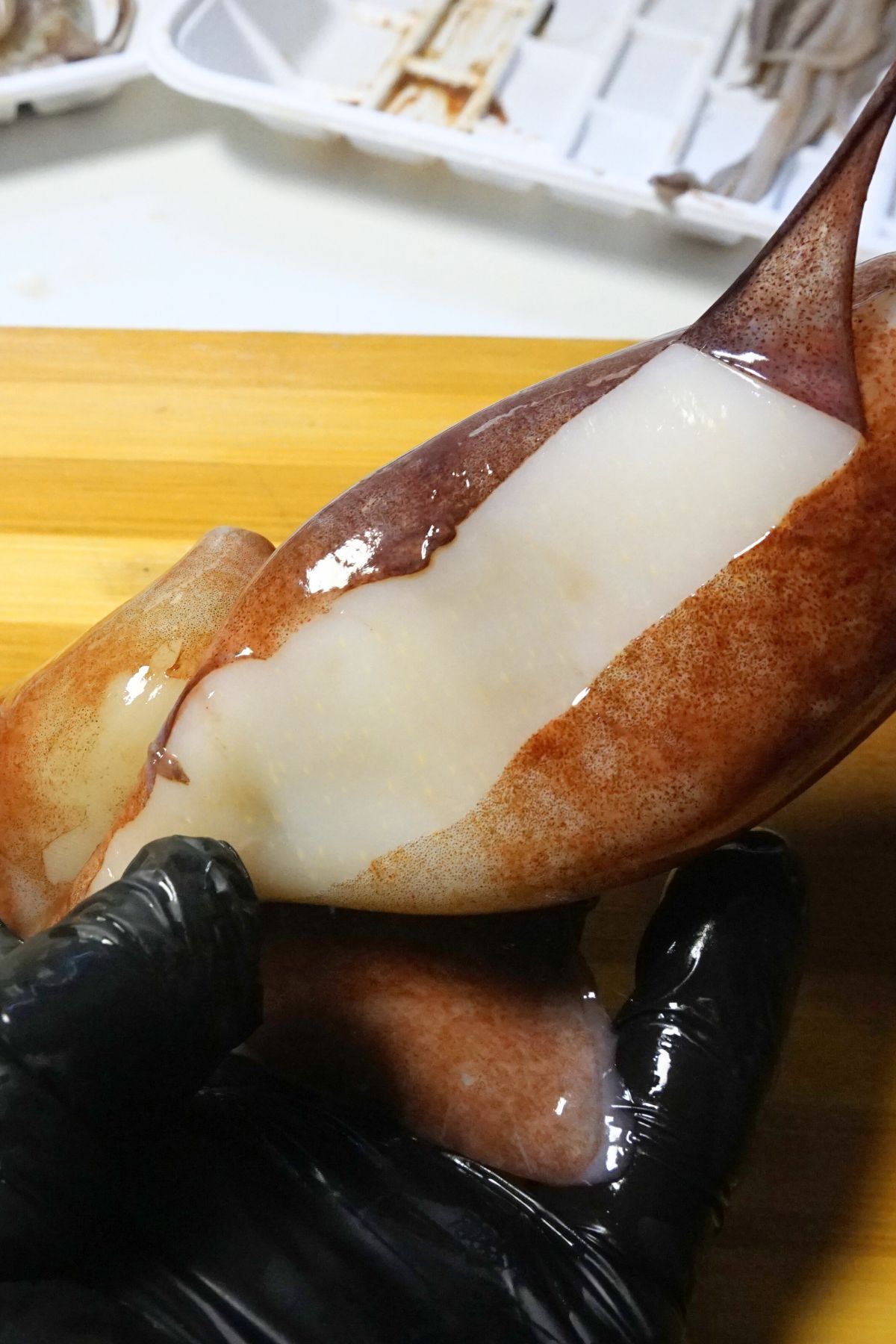 Gently peeling away the thin purple skin from the squid’s body.