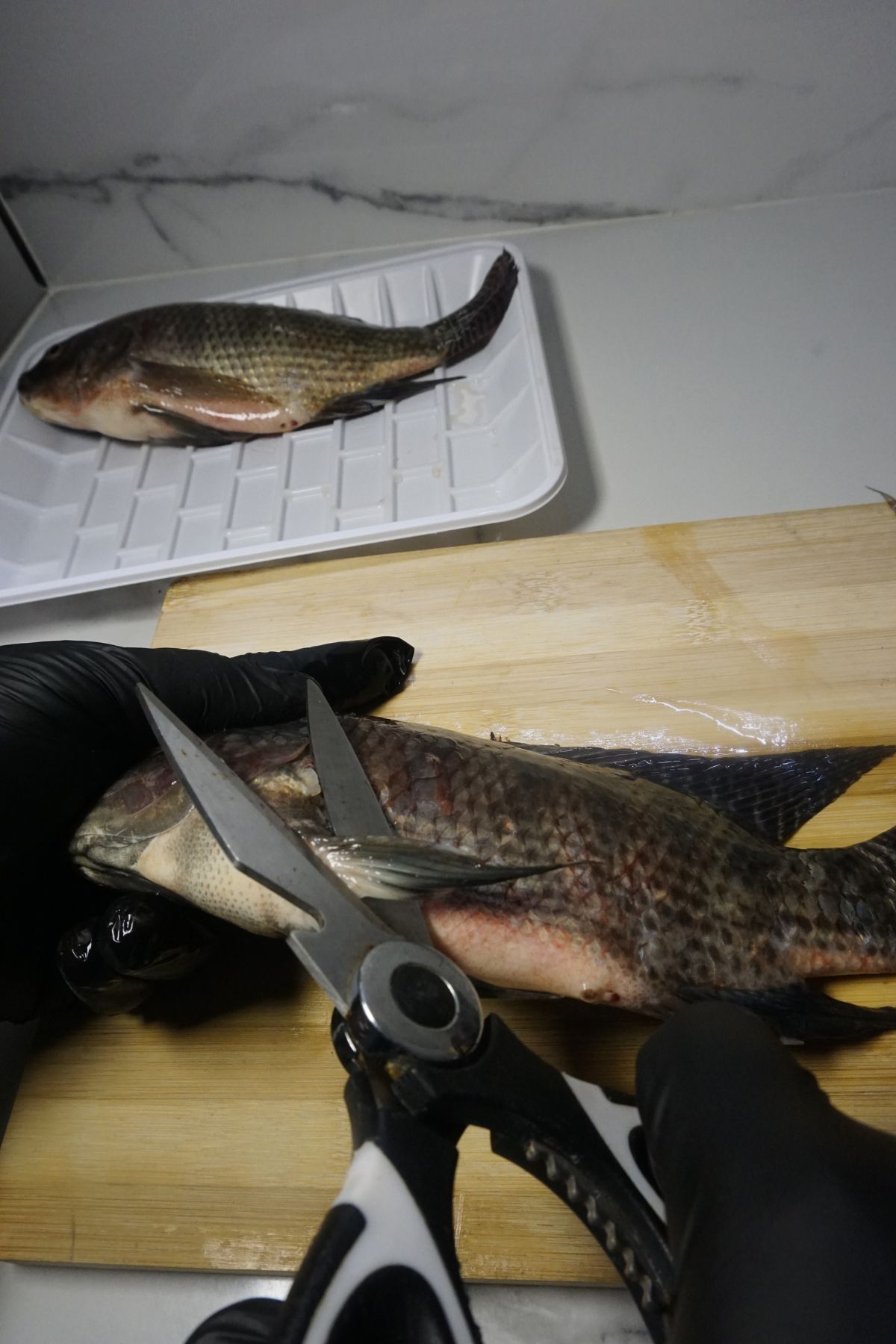 Cutting off the fins on the top, bottom, and sides of the tilapia