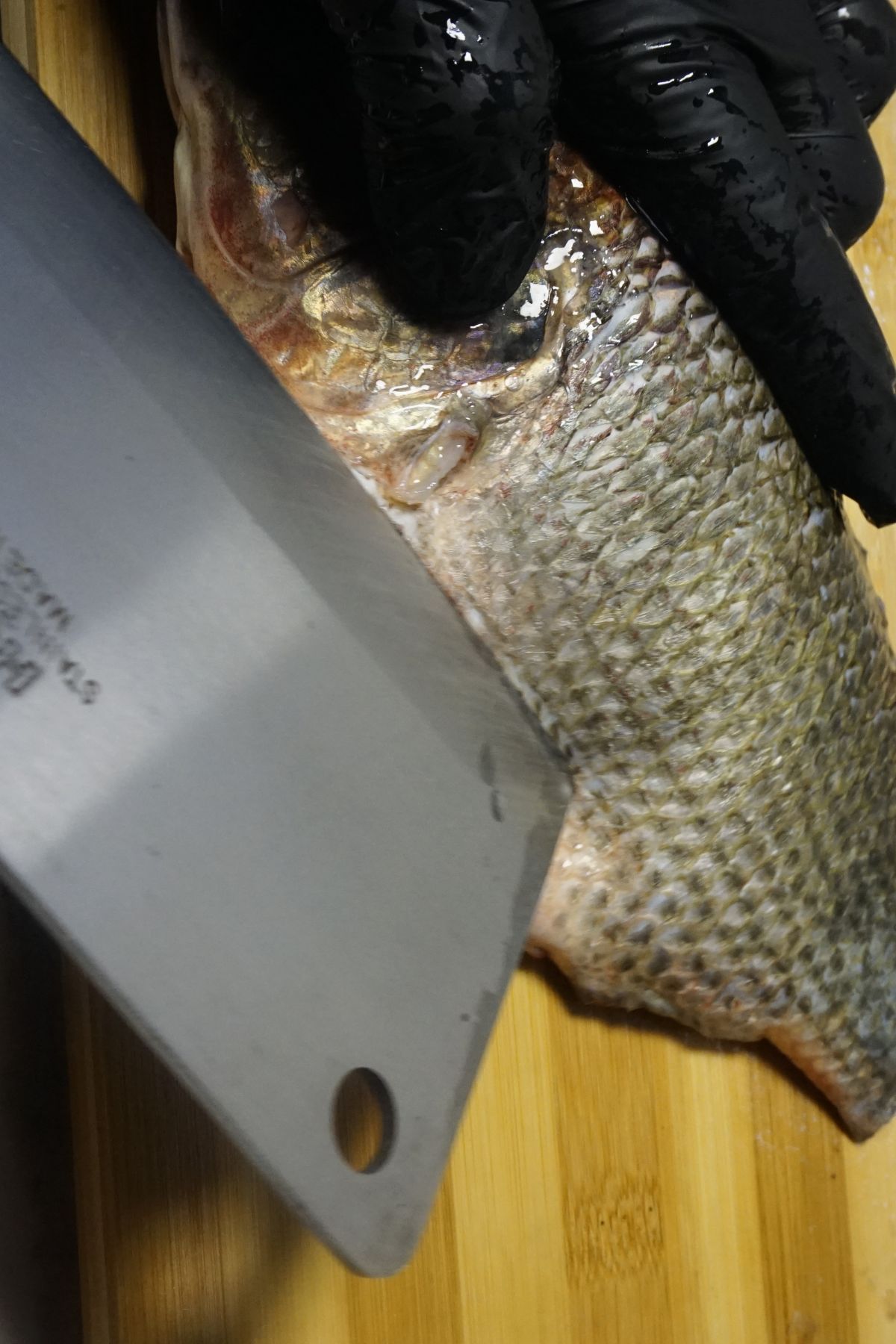 Slicing the tilapia&rsquo;s belly open using a sharp knife