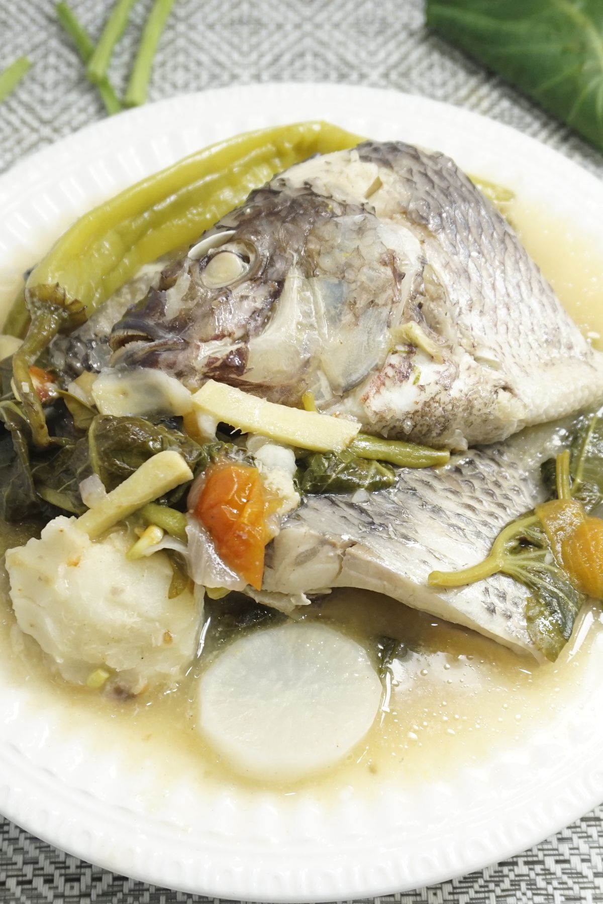 A serving of sinigang na tilapia in a white bowl.