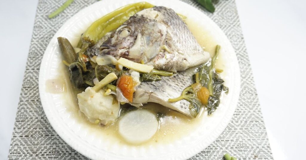 A serving of warm of sinigang na tilapia in white bowl.