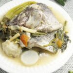 A serving of warm of sinigang na tilapia in white bowl.