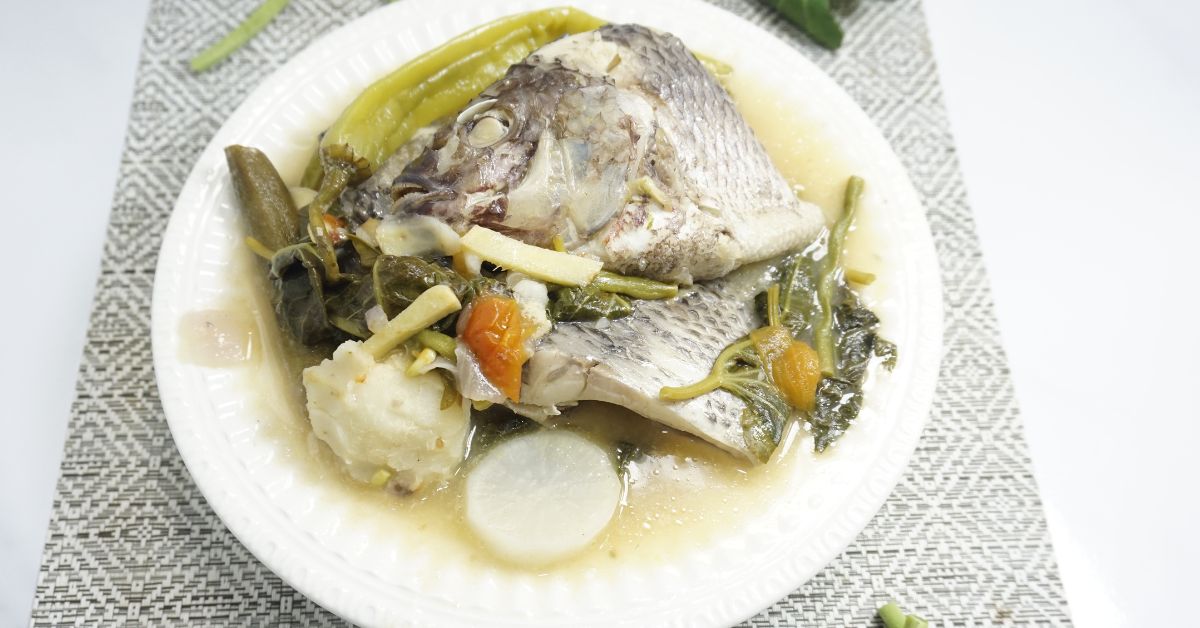 A serving of warm of sinigang na tilapia in white bowl.
